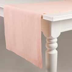 a white table with a pink cloth draped over it's top and two legs