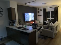 a living room filled with furniture and a flat screen tv mounted above a kitchen island