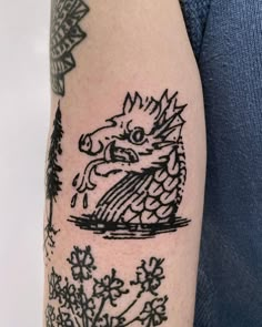 a black and white photo of a dragon tattoo on the left arm with flowers around it