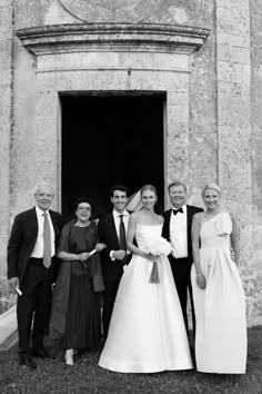 a group of people standing next to each other in front of a building with a doorway