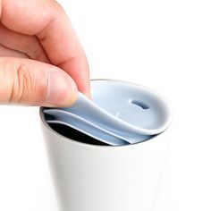 a hand is holding a spoon in a cup