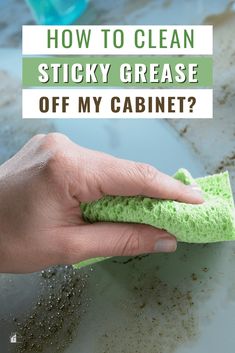 a hand holding a sponge on top of a counter with the words how to clean sticky grease off my cabinet?