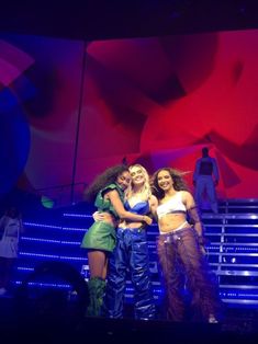 three women are standing on stage with their arms around each other