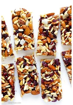 six bars with nuts and cranberry toppings cut into squares on a white surface