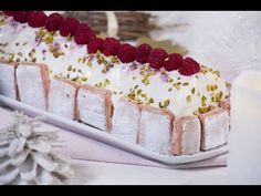 a dessert with raspberries and white frosting on a plate next to candles