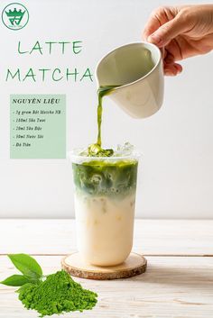 a person pouring green tea into a cup on top of a wooden table next to some leaves