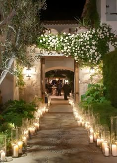 candles are lined up in front of the entrance to a building with flowers and greenery