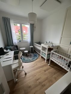 a baby's room with two cribs and a desk in the corner