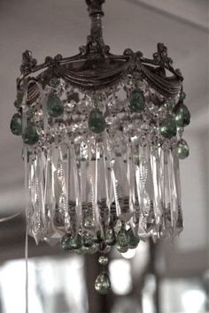 a chandelier with green glass beads hanging from it's sides in a room