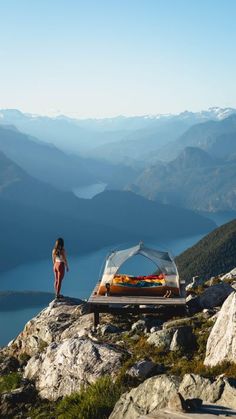 a woman standing on top of a mountain next to a picnic table