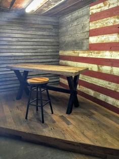 a table and stools sit in front of an american flag painted on the wall