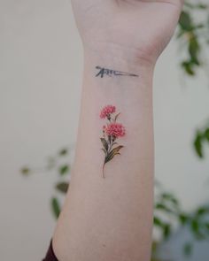 a woman's wrist tattoo with pink flowers on the left side of her arm