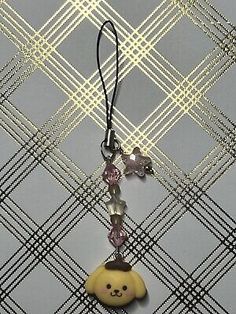 a necklace with a teddy bear on it hanging from a cord that is attached to a wall