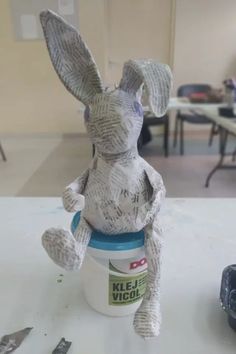 a stuffed animal sitting on top of a table next to a jar of paint and scissors