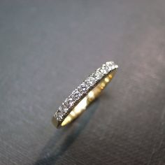 a gold ring with three rows of diamonds on the top and bottom, sitting on a black surface