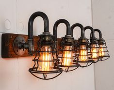 an industrial style light fixture is mounted on the wall with four lights and one bulb