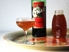 a bottle of wine and a glass on a plate with a drink next to it