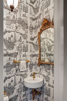 a bathroom with a sink, mirror and wallpaper on the walls in black and white