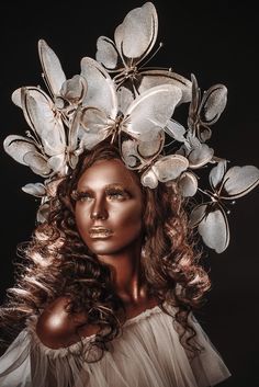 a woman with long hair wearing a headpiece made out of silver leaves and butterflies