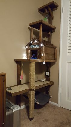 a cat tree that is made out of wood and has lights on the top shelf