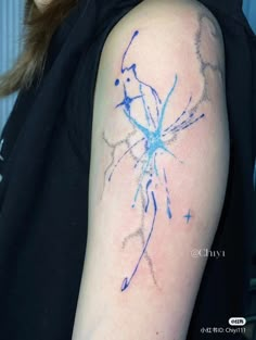 a woman with a tattoo on her arm that has blue ink splatters all over it