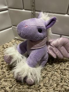 a purple stuffed animal sitting on top of a carpet