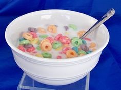 a white bowl filled with cereal on top of a blue table next to a fork