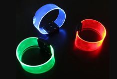 three glowing wristbands on a black background, one is red and the other is green