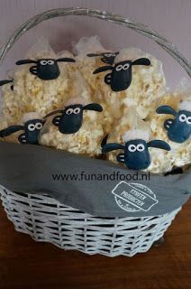 some sheep are sitting in a basket with popcorn on the table and one is black