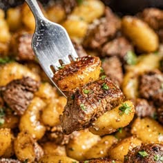 a close up of a fork with food on it in a skillet filled with potatoes