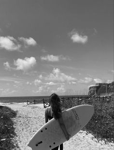 a woman holding a surfboard on top of a sandy beach