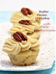 three cupcakes with white frosting and pecans on top are sitting on a plate