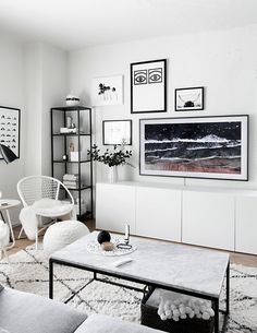 a living room filled with white furniture and pictures on the wall above it's coffee table