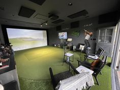 a man is playing golf on a large screen in a room with green carpeting