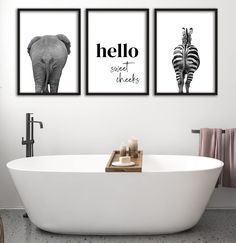 three black and white prints on the wall above a bathtub with an elephant, giraffe, and zebra