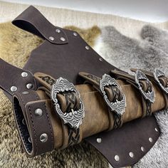 a brown leather belt with metal buckles and decorative decorations on the belt is laying on a fur rug