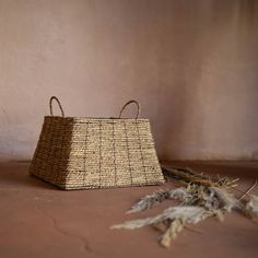 a basket sitting on top of a floor next to dry grass