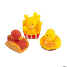 three rubber ducks sitting in front of a hot dog and cupcake with fries on it