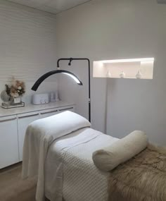 a white bed sitting next to a wall mounted shelf with lights on top of it