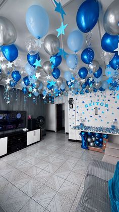 blue and silver balloons are hanging from the ceiling in this party - like room with white walls