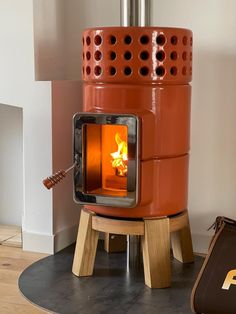 a wood burning stove sitting on top of a wooden floor next to a bag and suitcase