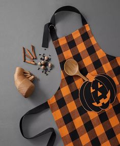 an orange and black plaid apron with a wooden spoon on it next to other items