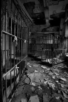 an old jail cell with bars and broken down doors in the middle of it is littered with debris