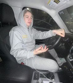 a woman sitting in the driver's seat of a car with headphones on