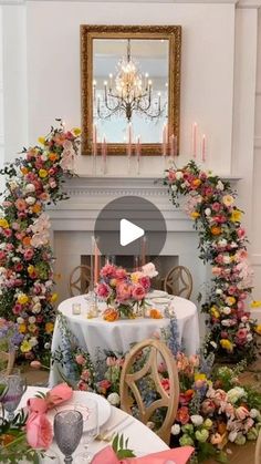 a table with flowers and candles is set up for a formal dinner in front of a fireplace