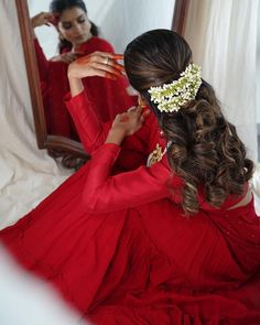 a woman sitting in front of a mirror wearing a red dress