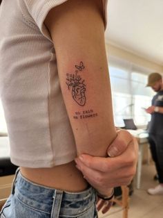 a woman holding her arm with a tattoo on it's left arm and the words,