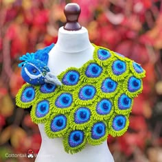 a green and blue crocheted scarf on a mannequin