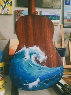 an acoustic guitar painted with the ocean wave on it's body, sitting on a table