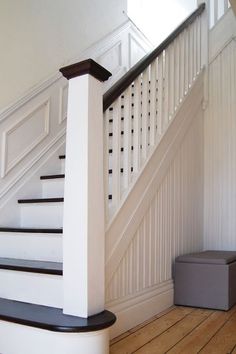 there is a stair case next to the banister in this house with white walls and wood flooring